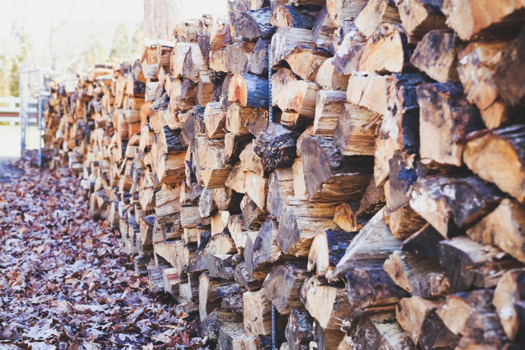 pexels-photo-1817017-1817017 A close-up of stacked firewood on a leaf-covered ground, showcasing texture and outdoor ambiance.